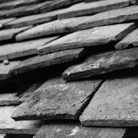 Slate Tile Roof Repair Services in Pleasanton, CA | Element Roofing Black-and-white close-up of aged, overlapping slate or concrete roof tiles needing repair in Pleasanton, California.