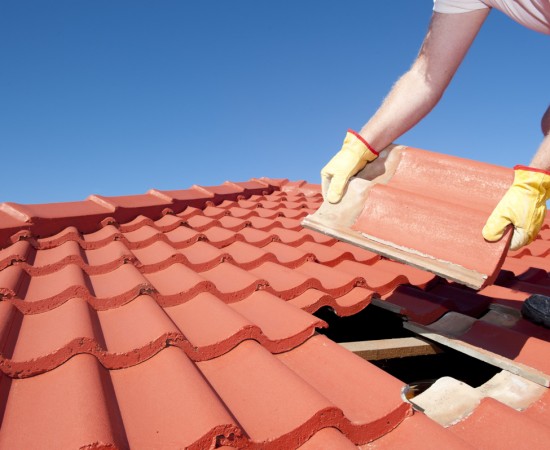 Danville CA Tile Roof Installation and Repair Roofer in protective gloves laying terracotta clay tiles on a residential roof in Danville CA