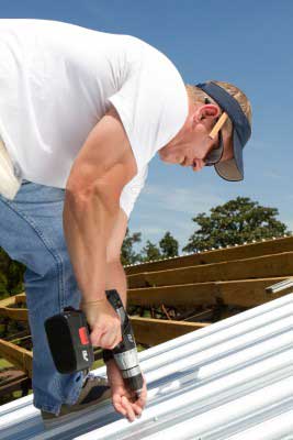 Roofer using a power drill to fasten white metal roofing panels in Orinda CA