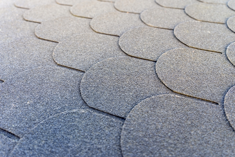 Close-up of interlocking scalloped grey roofing shingles on a commercial building in Concord