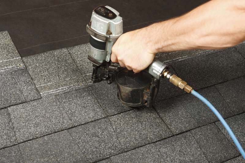 Pneumatic Roofing Installation and Shingle Repair in Antioch Roofer using a pneumatic coil nail gun to secure asphalt shingles on a roof deck in Antioch