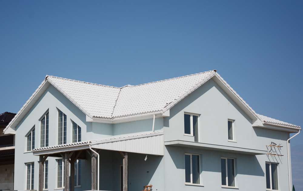 Energy Efficient Cool Roofing Installation in Pittsburg Two-story light grey stucco home featuring a white cool roof installation in Pittsburg