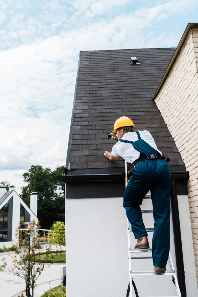 Repairman,In,Uniform,And,Helmet,Repairing,Roof,While,Standing,On